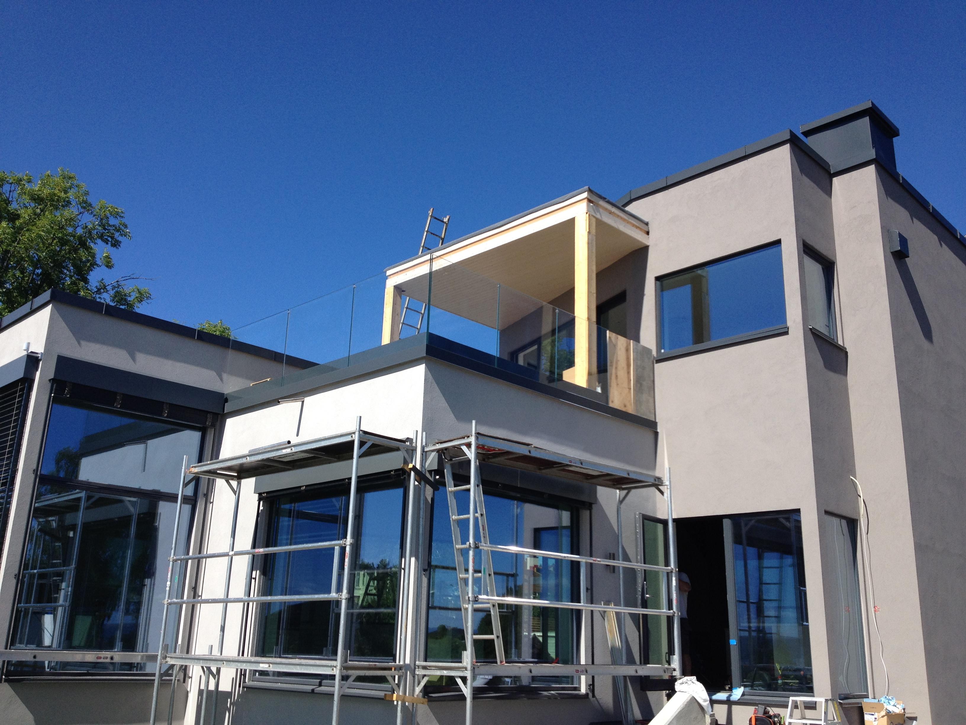 Moderne hus i hvit og grå puss med stillas og nye beslag